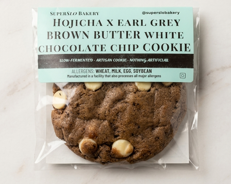 SuperSlo Bakery Hojicha Earl Grey Brown Butter White Chocolate Chip Cookie on a plate with tea leaves and a cup of tea.